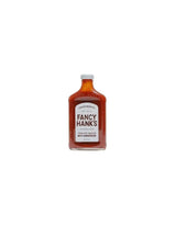 Fancy Hank's tomato sauce in a clear glass bottle with a white label on white background