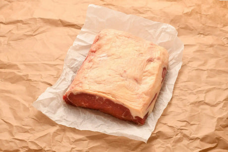 Raw Australian sirloin steak with thick fat cap on parchment paper