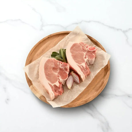 Free range almond pork loin chops with fresh herbs and shallots on a wooden plate