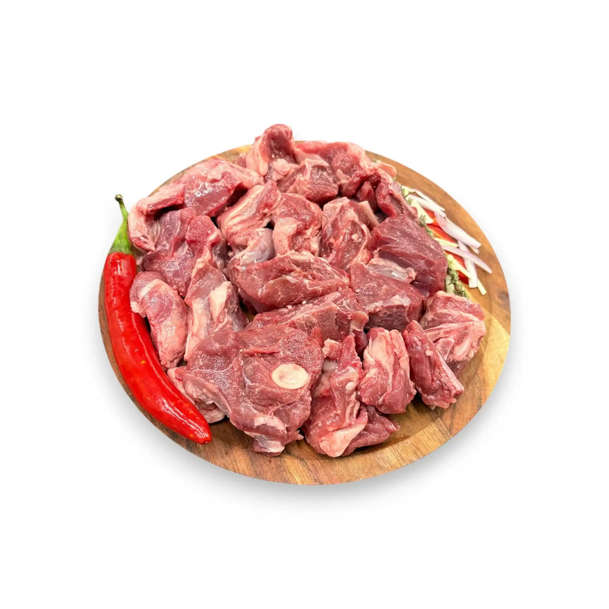 Fresh raw beef chunks on wooden board with red chili and herbs, ideal for stew or braising