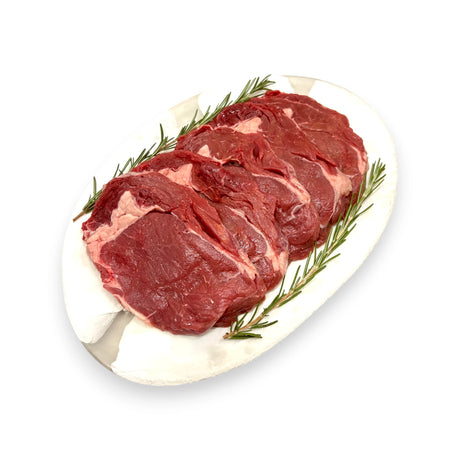 Raw beef steaks on a white plate with rosemary sprigs on a white background