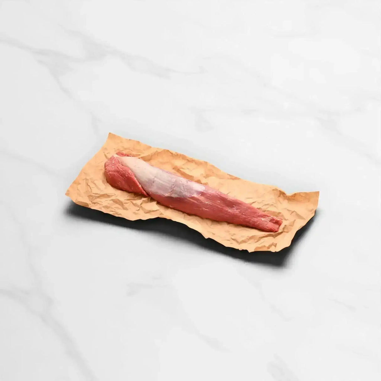 Raw grain fed whole eye fillet beef on butcher paper, marble background