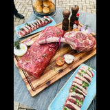Display of premium Australian beef cuts with herbs and onions on a wooden board, outdoor setting