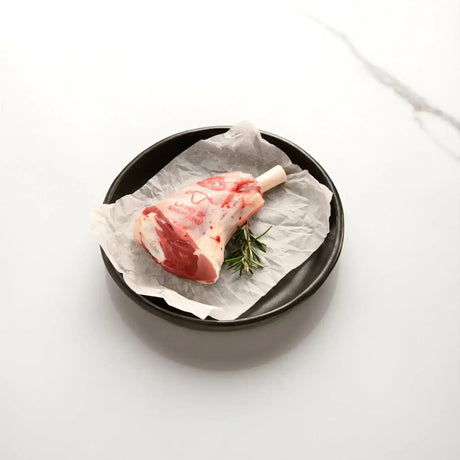 Raw lamb shank with rosemary on parchment in a black dish, Peter Augustus Craft Butcher