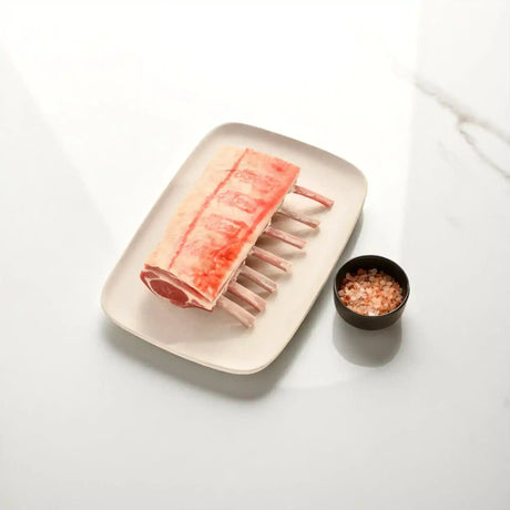 French trimmed lamb rack on a plate beside a bowl of gourmet salt from Peter Augustus Craft Butcher