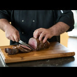 Chef slicing juicy roast beef on wooden cutting board, showcasing premium Australian meat