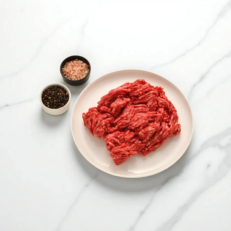 Fresh Australian beef mince on white plate with bowls of peppercorns and pink salt from Peter Augustus
