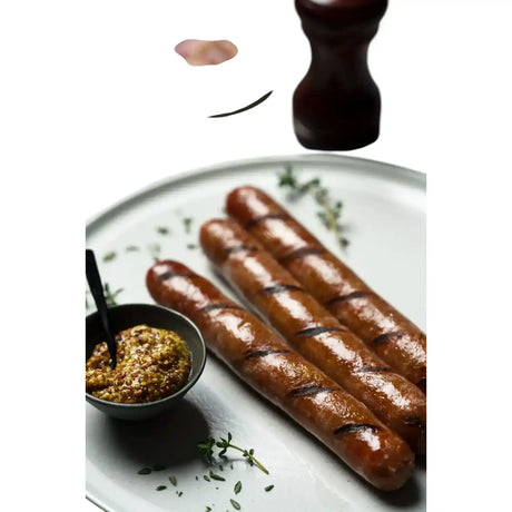 Grilled Angus beef sausages with mustard and herbs on a white plate