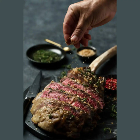 Hand seasoning sliced cooked Australian Wagyu Tomahawk steak by Peter Augustus