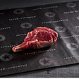 Raw bone-in ribeye steak on branded Peter Augustus butcher paper, premium Australian beef