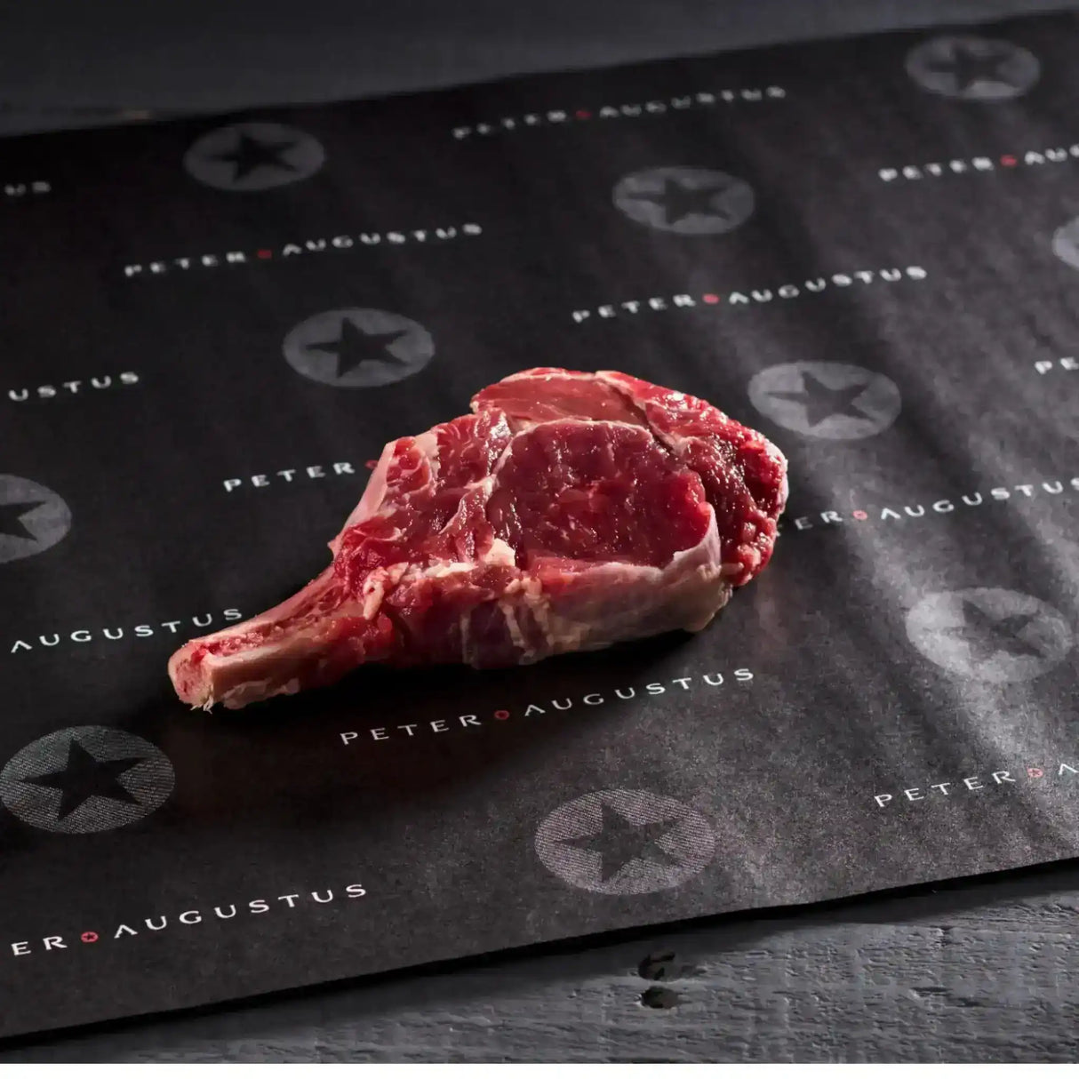 Raw bone-in ribeye steak on branded Peter Augustus butcher paper, premium Australian beef