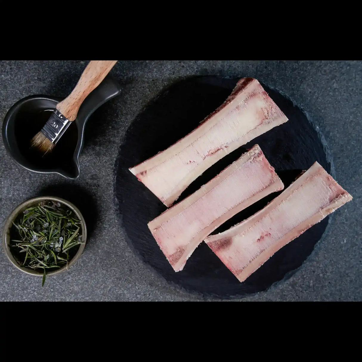 Peter Augustus Australian beef marrow bones with herbs and basting brush on slate plate