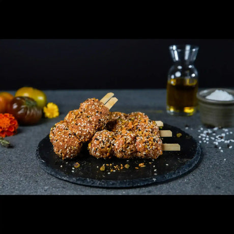 Raw seasoned beef skewers with sesame seeds on a black slate, gourmet butcher display