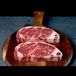 Two marbled Australian beef steaks on a wooden board from Peter Augustus Craft Butcher