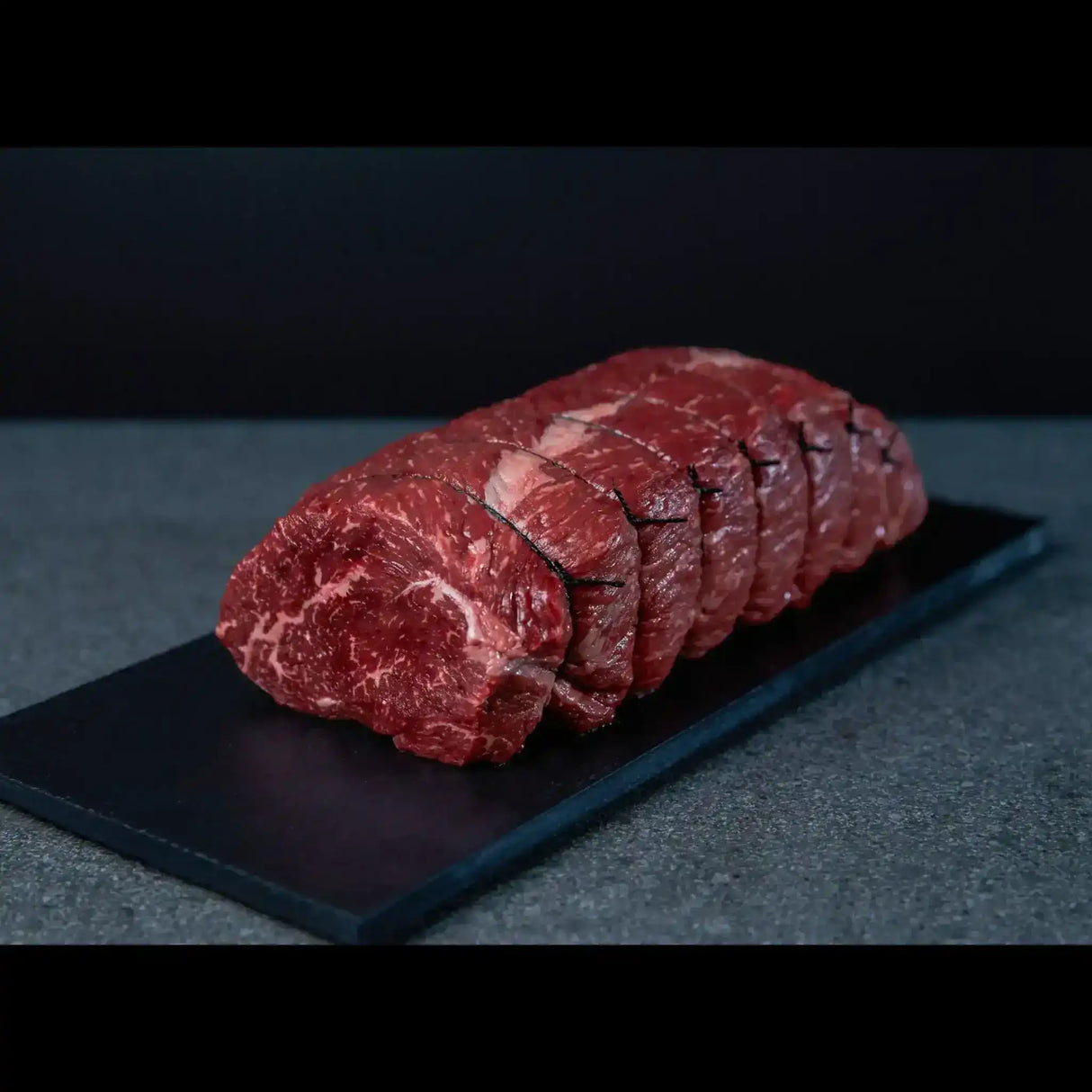 Sliced marbled Australian beef on a black slate board, gourmet butcher meat display