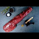 Whole raw Wagyu eye fillet on stone with rosemary, salt, pepper and basting brush