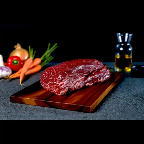 Premium Australian Wagyu eye fillet steak on board, vegetables and oil in background