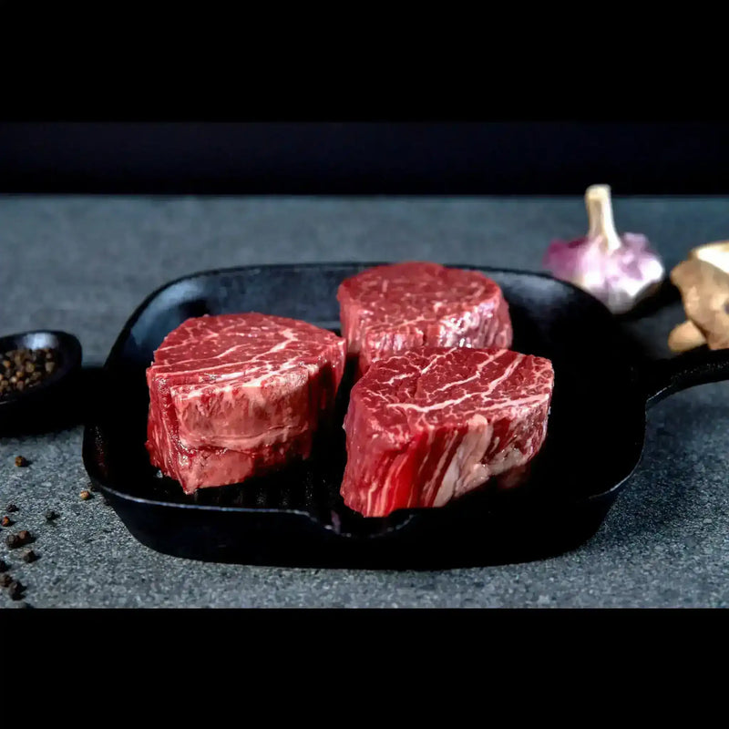 Three raw Wagyu eye fillet steaks in a cast iron pan, premium beef by Peter Augustus