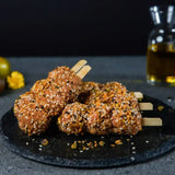 Raw seasoned Lamb skewers with sesame seeds on a black slate, gourmet butcher display