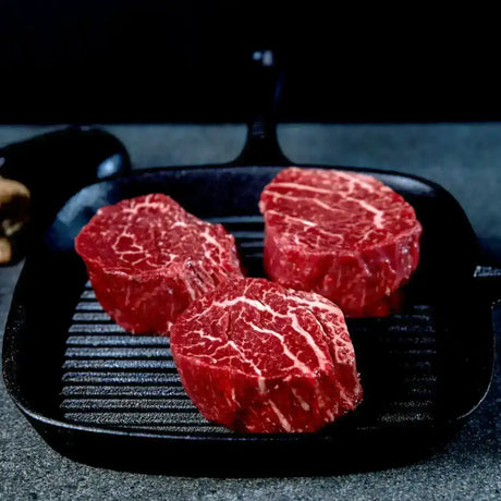 Three raw Australian eye fillet steaks with rich marbling on a grill pan from Peter Augustus