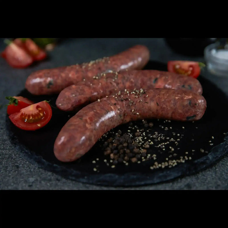 Peter Augustus gourmet raw beef sausages with cracked pepper and tomatoes on slate plate