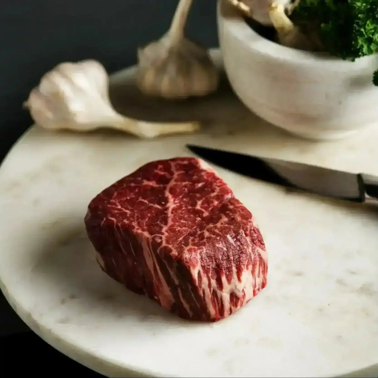 Raw Wagyu beef tenderloin eye fillet steak on marble board with garlic and knife