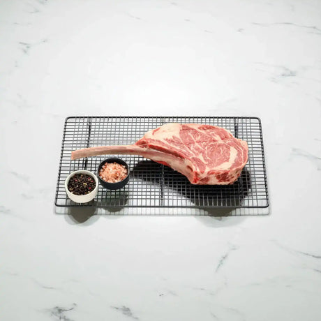Australian Angus Tomahawk steak with peppercorns and pink salt on wire rack from Peter Augustus