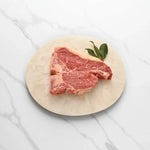 Premium raw Florentine steak on a round plate with fresh bay leaves from Peter Augustus