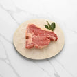Raw Florentine steak from Peter Augustus Craft Butcher on a round platter with bay leaves