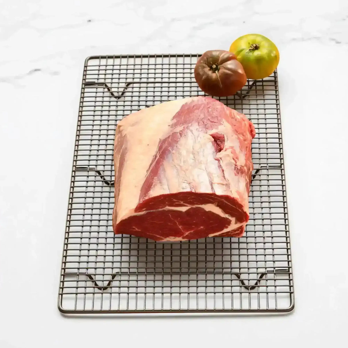 Premium Australian rib fillet piece from Peter Augustus Craft Butcher on wire rack with tomatoes