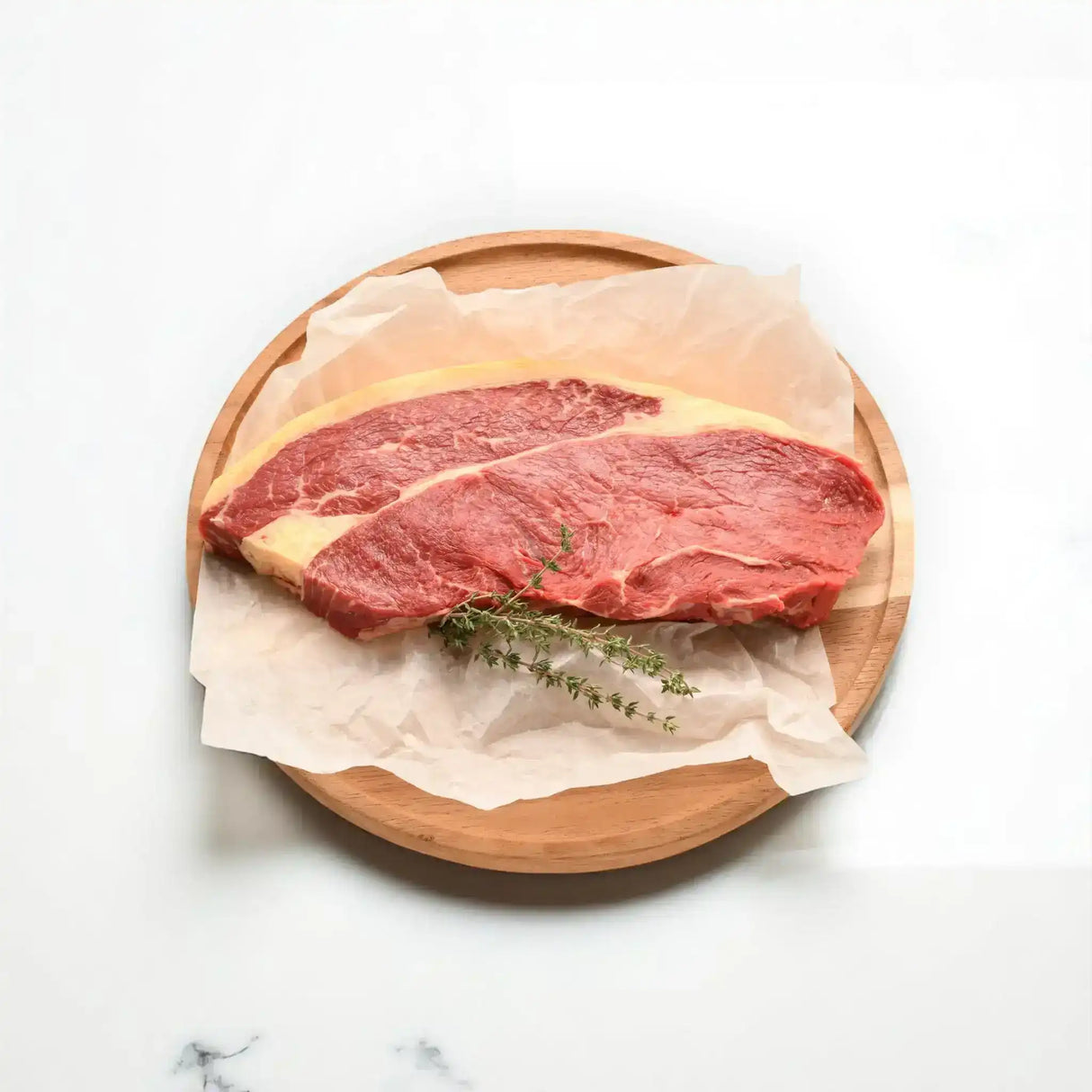 Premium Australian rump steak from Peter Augustus Craft Butcher on a wooden board with herbs