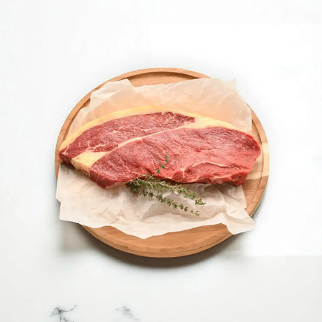 Premium Australian rump steak from Peter Augustus Craft Butcher on a wooden board with herbs