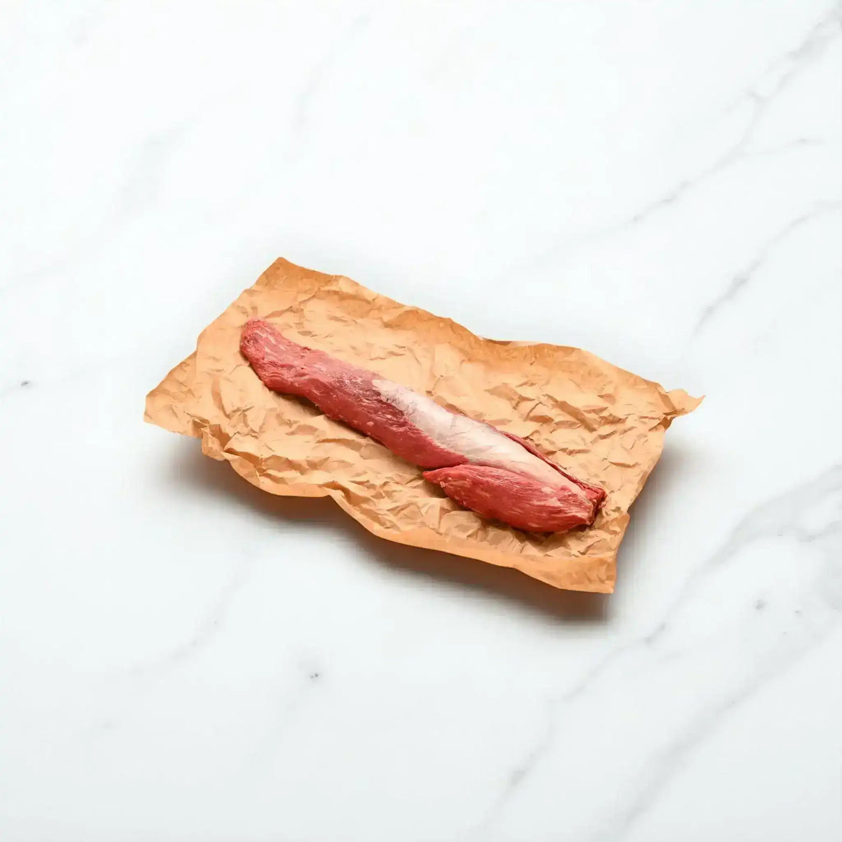 Whole Wagyu eye fillet steak on butcher paper, raw, on a white background