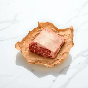 Wagyu sirloin steak cut with marbled beef on brown butcher paper, white marble background