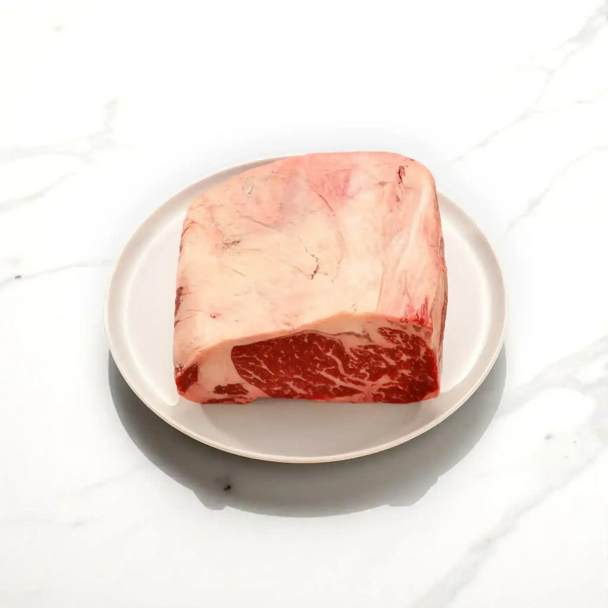 Raw Australian Wagyu sirloin steak with marbling on a white plate, marble background