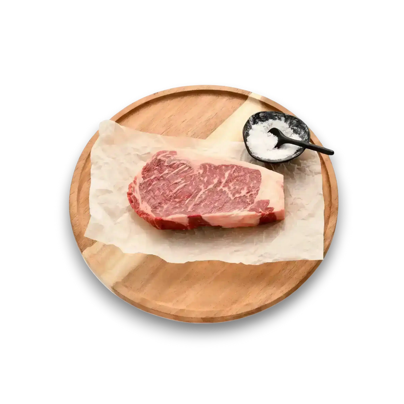 Marbled Wagyu steak on parchment paper with sea salt, served on a wooden platter