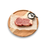 Marbled Wagyu steak on parchment paper with sea salt, served on a wooden platter