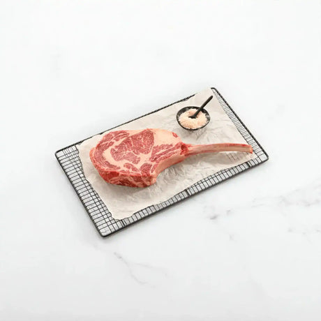 Australian Wagyu tomahawk steak with marbling, served raw on tray with salt, Peter Augustus