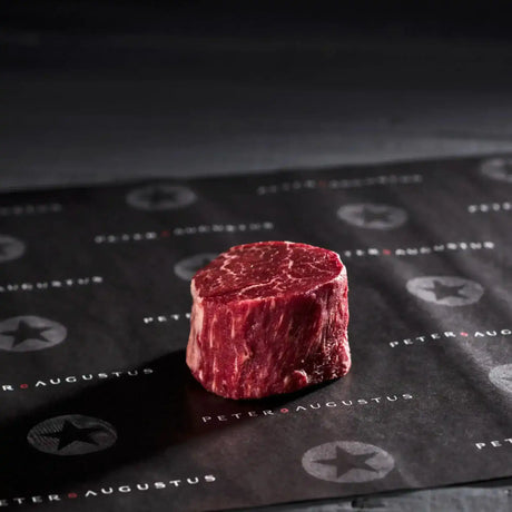 Raw Australian eye fillet steak with marbling on black butcher paper