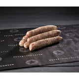 Raw pork provolone sausages stacked on black butcher paper, gourmet sausage product