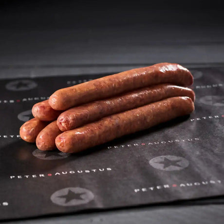 Four raw beef sausages stacked on black butcher paper