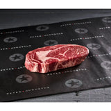 Fresh marbled ribeye steak on branded butcher paper, premium Australian beef cut