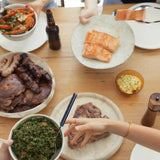 Table with grilled beef, sausages, salmon fillets, salad, and herb butter