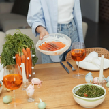 Fresh salmon slices served on a plate at a festive dinner table with wine and vegetables