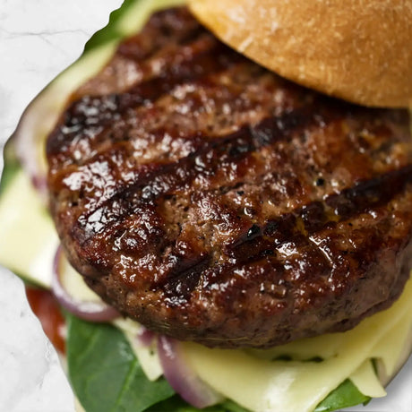 Juicy grilled Wagyu beef burger patty on artisan bun with cheese, onion and greens
