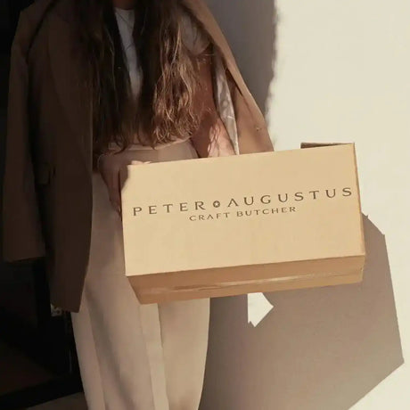 Woman holding Peter Augustus Craft Butcher delivery box in natural sunlight