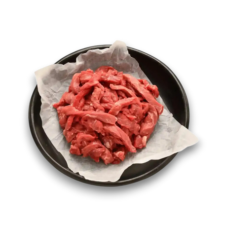 Freshly sliced beef strips on parchment paper, ideal for stir-fry or grilling