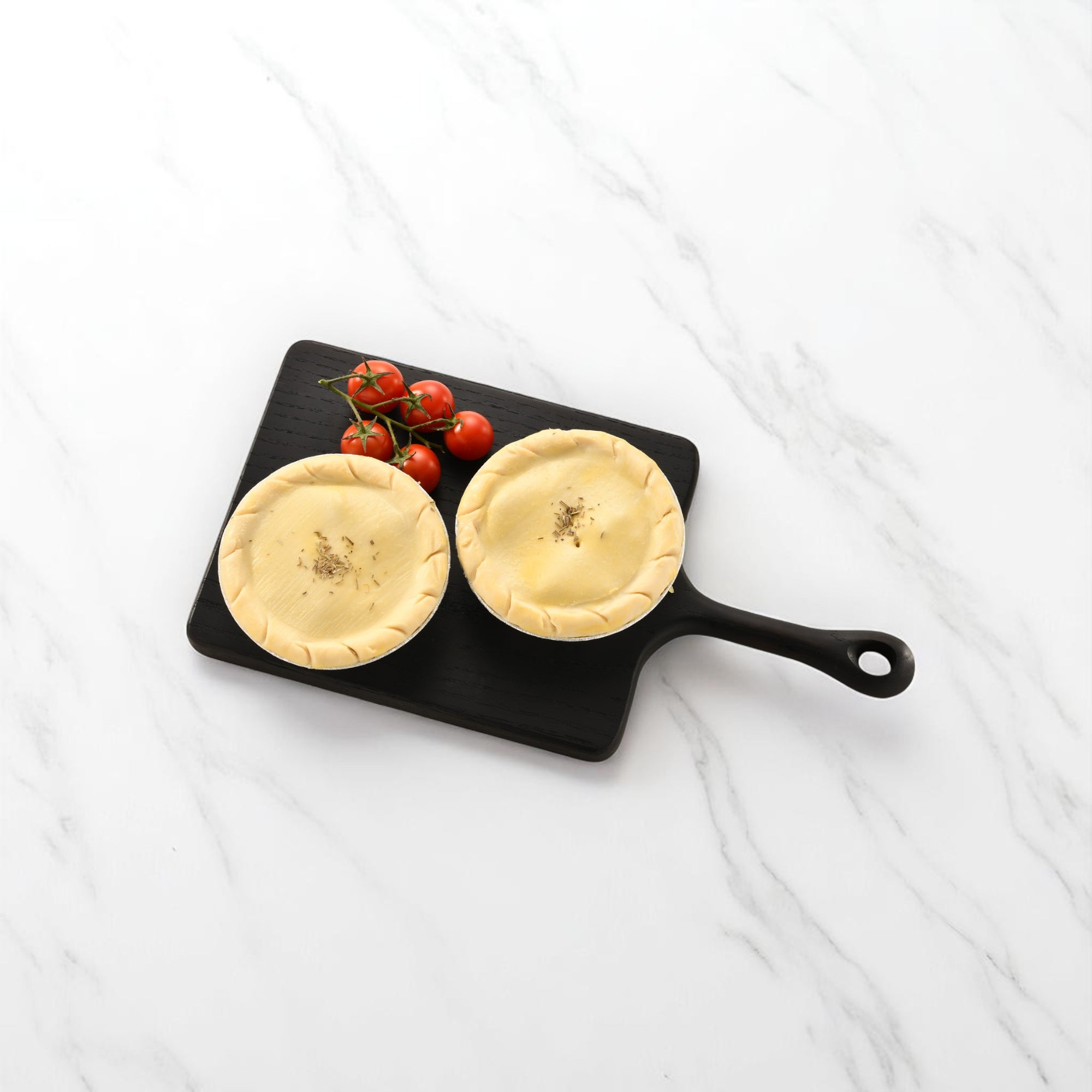 Two golden-brown chicken and bacon pies on a wooden board, ready to serve.