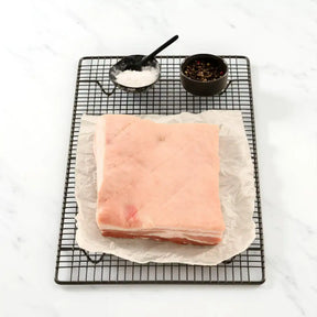 Uncooked pork belly slab on parchment paper with salt and pepper, Peter Augustus Craft Butcher