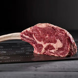 Raw tomahawk steak with rich marbling on a dark butcher paper, premium beef cut